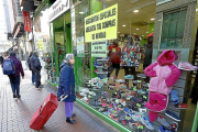 Una mujer con un carrito de compra observa las ofertas de un escaparate en la calle Teresa Gil.-J.M.LOSTAU