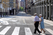 Dos ancianos cruzan una céntrica calle sin coches en la calzada.-MIGUEL ÁNGEL SANTOS