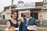 Alfonso y Alicia, con las patatas revolconas y una pieza de carne, a la entrada del establecimiento.-ARGICOMUNICACIÓN