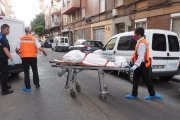 Dos operarios sacan a uno de los cadáveres del edificio en la calle Linares.- E.M.