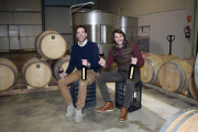 Nacho y Julio, en la sala de barricas de su bodega con dos botellas de Taruguín.