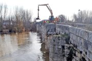 Una grúa recoge material de la riada en el puente de Simancas.-EL MUNDO