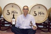 Benjamín García en su diminuta nave de crianza con una botella y el hierro que da nombre a su bodega en Sejas de Aliste.-