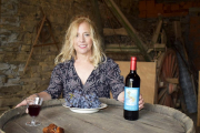Teodora López en el interior de la bodega familiar con un racimo de uvas de tinta mencía y el primer vino que se embotella en su pueblo.-E. M.