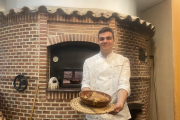 Andoni, frente al horno de leña que se encuentra en el interior del Villa de Frómista, con uno de sus cuartos de lechazo.- E.M.