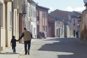 Un niño camina cogido de la mano de su padre por las calles de un pueblo de Valladolid, en una imagen de archivo.- J.M. LOSTAU