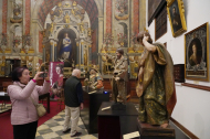 Una mujer fotografía unas tallas de Santiago Apóstol y San Juan Apóstol
