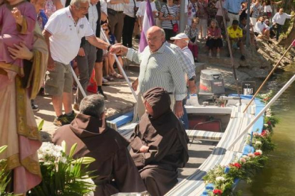 Carnero ayuda a subir a la barca a un pasajero de la barca en la procesión del Carmen