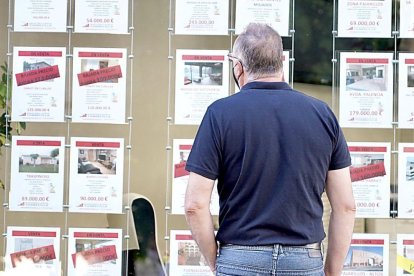 Un vecino observa las ofertas de pisos en venta y alquiler en una inmobiliaria de Valladolid. ICAL
