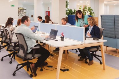 Varias personas alrededor de una mesa con sus portátiles.