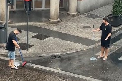 Los dos jóvenes tratando de achicar el agua de la granizada en Valladolid con fregonas y escobas