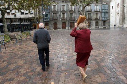 Una señora se protege de la lluvia con su bolso en la plaza de la Universidad