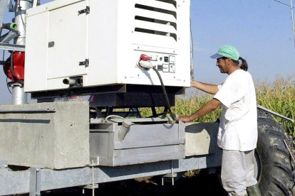 Un agricultor, con un pívot de riego en una plantación de maíz, en una imagen de archivo