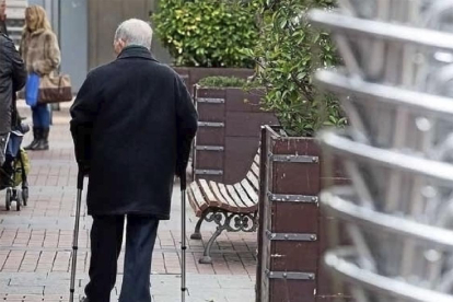 Un anciano pasea por una calle de Valladolid apoyado en dos muletas.-E. M.