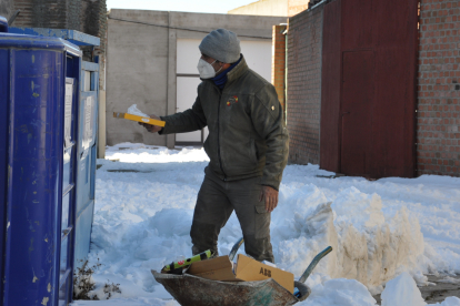 Un vecino de Fuente del Sol tira cartones al contenedor rodeado de nieve. SANTIAGO G. DEL CAMPO