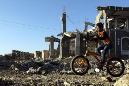 Un niño yemení pasea con su bicicleta junto a los escombros de una vivenda en Saná destrozada por los bombardeos aéreos.-YAHYA ARHAB (EFE)