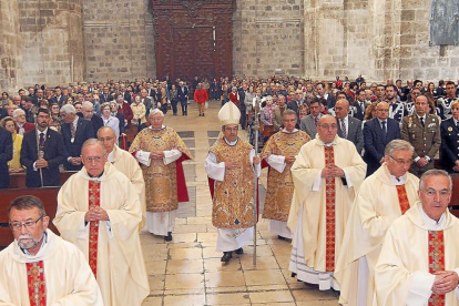 El obispo auxiliar, Luis Argüello, flanqueado por presbíteros, se dirige al altar mayor de la Catedral-