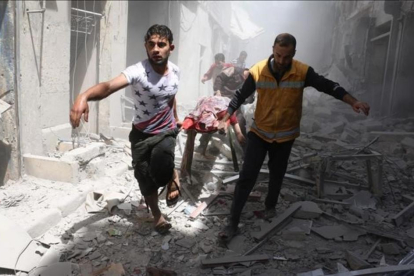 Dos hombres evacúan a una persona víctima de los bombardeos de hoy en el barrio de Al Qatarji de Alepo.-AFP / AMEER ALHALBI