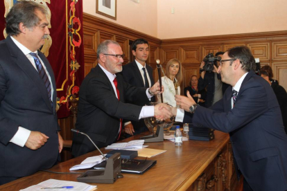 El recién elegido alcalde de Palencia, Alfonso Polanco, recibe el bastón de mando de manos del concejal de mayor edad, el socialista Jesús Merino.-Ical