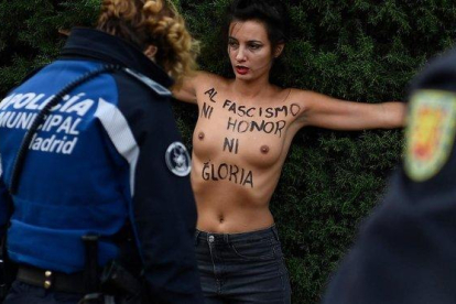 Un agente policial retiene a una activista de Femen, este domingo, en la Plaza de Oriente de Madrid.-AFP / ÓSCAR DEL POZO