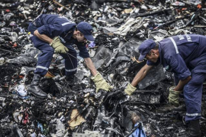 Dos agentes buscan entre los restos del vuelo MH17 de Malaysia Airlines, el pasado 20 de julio en Donetsk (Ucrania).-Foto: AFP / BULENT KILIC