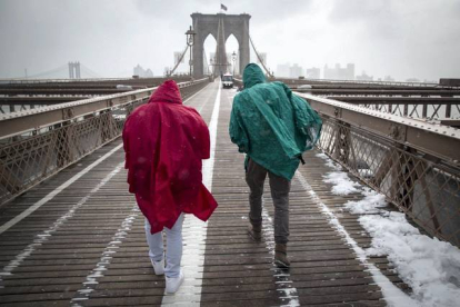Dos turistas atraviesan el puente de Brooklyn en medio de una tormenta de nieve en Nueva York, Estados Unidos, hoy, lunes 26 de enero de 2015. Más de dos mil vuelos han sido cancelados hoy en la ciudad y en el nordeste del país debido al temporal de nieve que afectará con fuerza en las próximas horas a la región, según informes de las compañías aéreas. ANDREW KELLY | EFE
