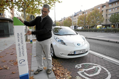 Un hombre recarga su vehiculo en un punto destinado a coches eléctricos.-MIGUEL ÁNGEL SANTOS