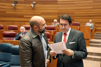 El consejero de Fomento y Medio Ambiente, Juan Carlos Suárez-Quiñones, conversa con el procurador de Podemos Ricardo López, antes de comenzar el Pleno de las Cortes de Castilla y León-ICAL