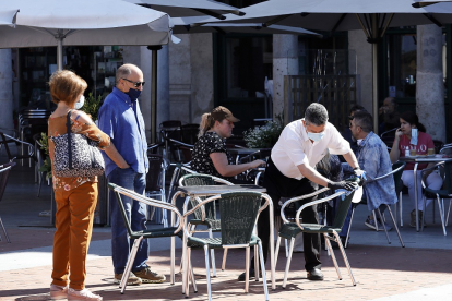 Unos clientes esperan a que el camarero desinfecte la mesa en una terraza de la Plaza Mayor. - J.M. LOSTAU