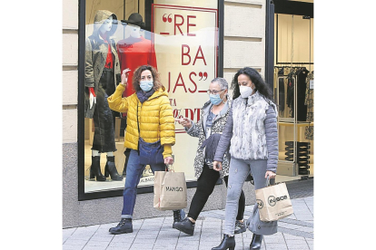 Tres compradoras pasan por delante del escaparate de una tienda que anuncia rebajas en Valladolid.- J. M. LOSTAU