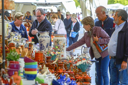 Varias personas contemplan los productos en la Feria de Cerámica y Artesanía de la Acera de Recoletos.