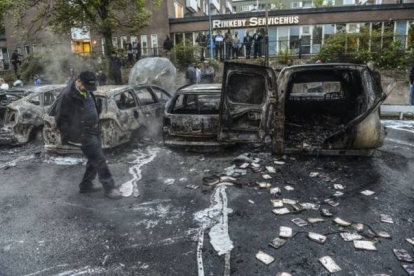 Un hombre camina junto a una hilera de coches carbonizados tras unos disturbios en mayo del 2013, en un suburbio de Estocolmo.-Foto: EFE / FREDRIK SANDBERG