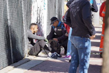 El joven que se encaramó a la grúa, sentado en la acera tras bajar, mientras  un policía inspecciona la mochila. PHOTOGENIC