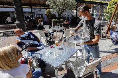 Unos clientes esperan a que el camarero desinfecte la mesa en una terraza de la Plaza Mayor. J.M. LOSTAU
