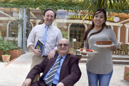 Félix, con su novela ‘Desahucio’, junto a su padre (sentado) y su pareja, Kimberly, que atiende el comedor del restaurante.-ARGICOMUNICACIÓN