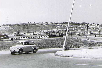 Un Seat 600 circula con el barrio Girón al fondo en los años 70. ARCHIVO MUNICIPAL