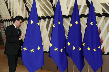 Un funcionario prepara las banderas de la Unión Europea antes del inicio de la cumbre, este domingo en Bruselas.-AFP