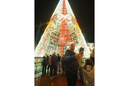Un varón se fotografía con el árbol de Navidad de la plaza Mayor de Valladolid. PHOTOGENIC