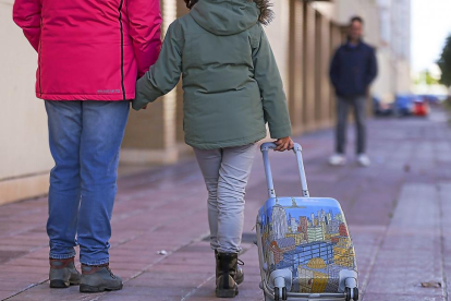 Una niña camina portando una maleta entre sus progenitores.-MIGUEL ÁNGEL SANTOS (PHOTOGENIC)