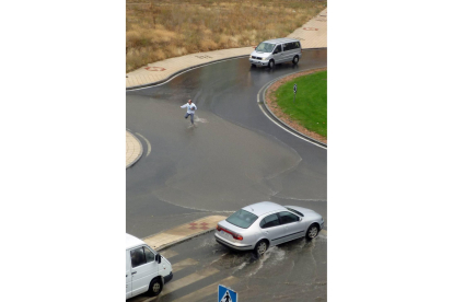 Un hombre intenta cruzar la calle en el barrio de la Universidad momentos después de una tormenta en Ávila-Ical