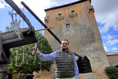 Millán Bermejo, apoyado en una recreación de un arma de asedio medieval, frente al Torreón de Fernán González de Covarrubias.