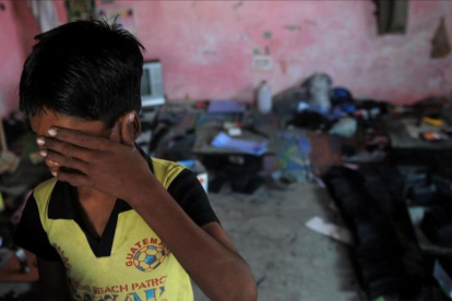 Un niño indio se cubre la cara en un suburbio de Delhi.-MANAN VATSYAYANA