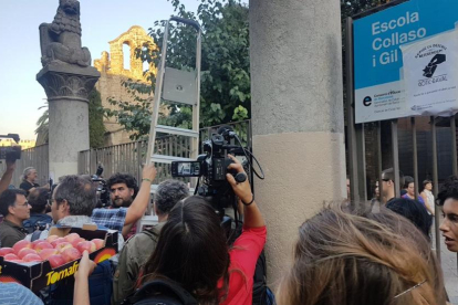 Los mossos se han ido y varias personas entran la escuela Collaso i Gil con la ayuda de una escalera entre aplausos-ROGER PASCUAL
