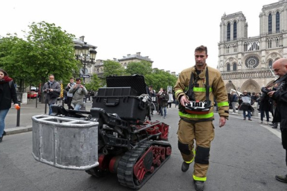 Un bombero, junto con el robot que ayudó a los bomberos en el incendio de Notre Dame, este martes.-REUTERS / YVES HERMAN