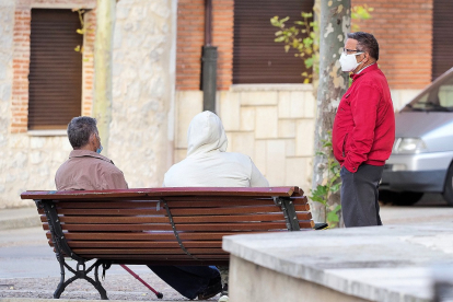 Vecinos de Pedrajas de San Esteban dialogan con sus mascarillas en un banco instalado en una plaza de la localidad. - PABLO REQUEJO