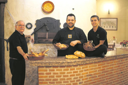 Rubén García junto a su tío Pedro García y su hijo Sergio, a la puerta del horno de asar de leña en el comedor del restaurante.-