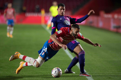 Real Valladolid's Brazilian forward Marcos Andre (back) fouls Granada's French midfielder Maxime Gonalons during the Spanish League football match between Granada FC and Real Valladolid FC at the Nuevo Los Carmenes stadium in Granada on November 22, 2020. (Photo by JORGE GUERRERO / AFP)