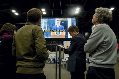 Los periodistas, siguiendo la rueda de prensa de David Cameron por la televisión. LEON NEAL | AFP