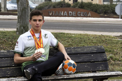 El jugador Sergio Casares posa con sus medallas en los campeonatos de España delante del cartel que da la bienvenida a Viana.-PABLO REQUEJO
