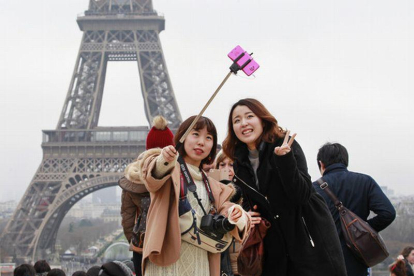Turistas utilizando del palo para hacerse selfis en París.-